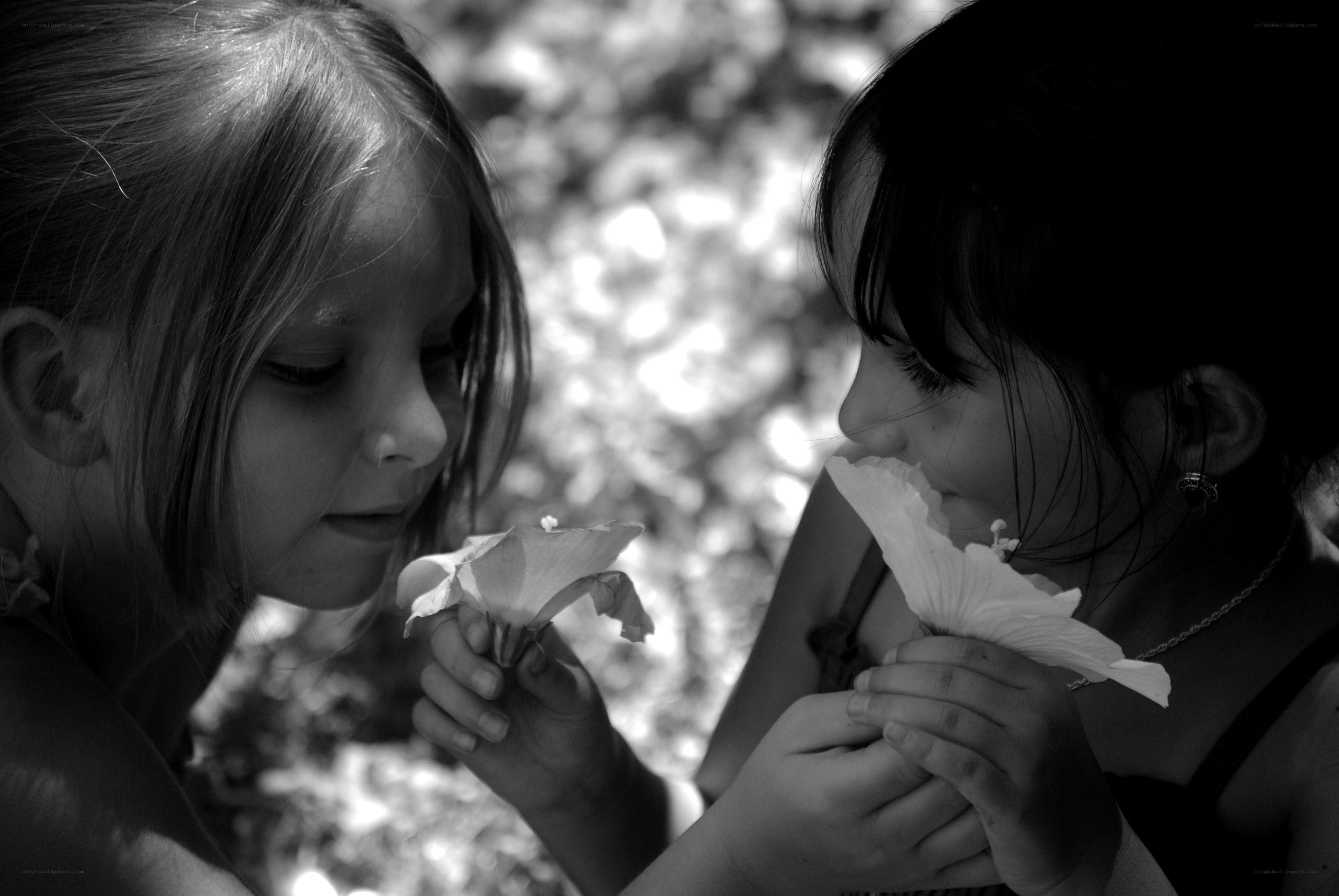two girls smelling flowers