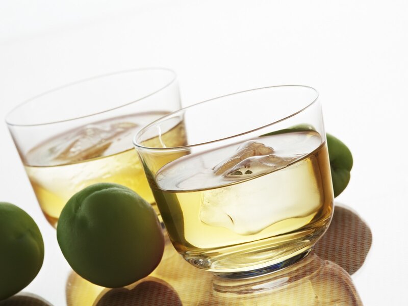 Two glasses of whiskey with ice and plums