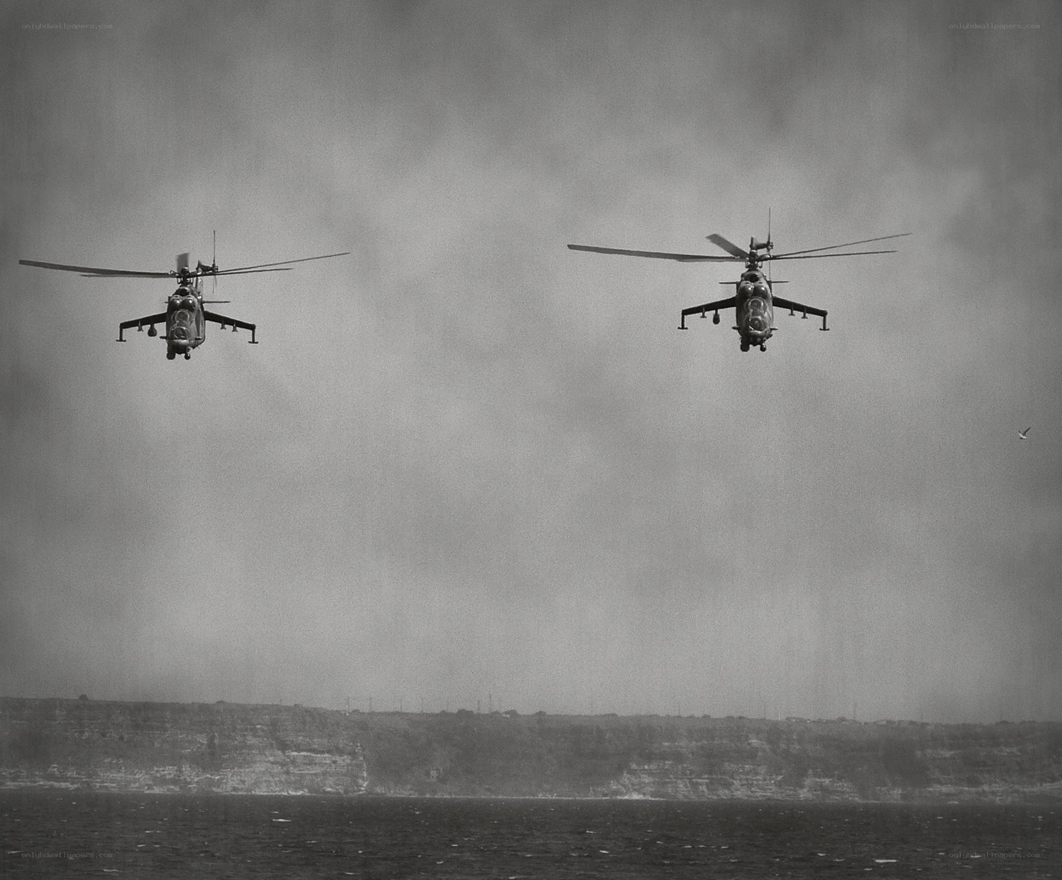 Two helicopters flying over water
