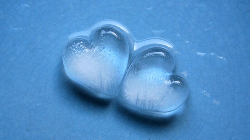 Two ice hearts on blue surface