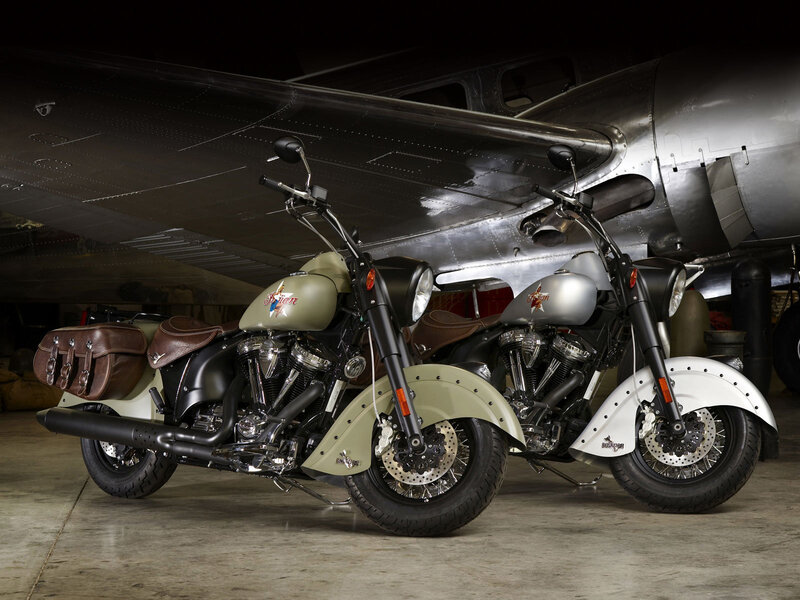 Two Indian motorcycles under an airplane