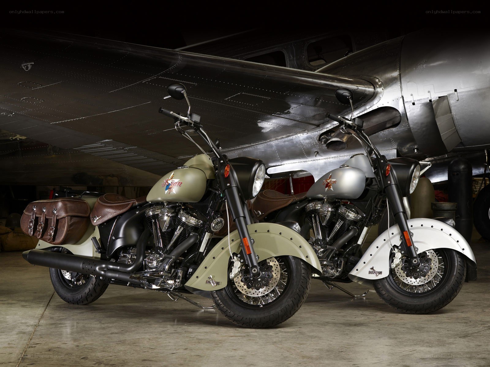 Two Indian motorcycles under an airplane