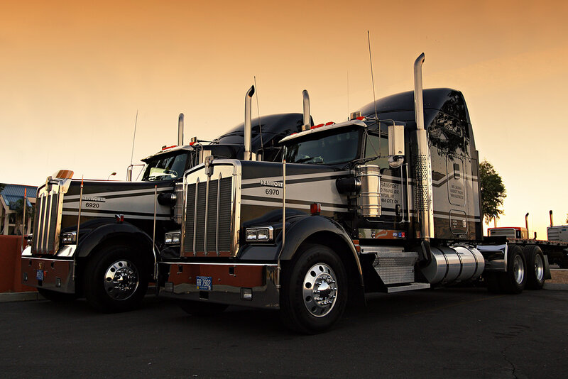 Two Kenworth trucks at sunset