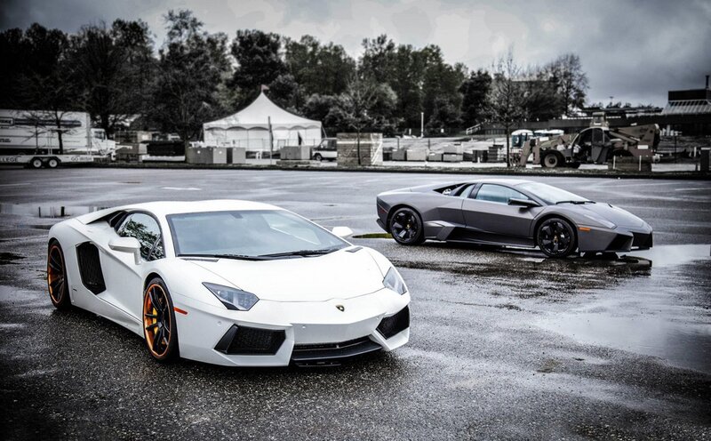 Two Lamborghini supercars on wet pavement