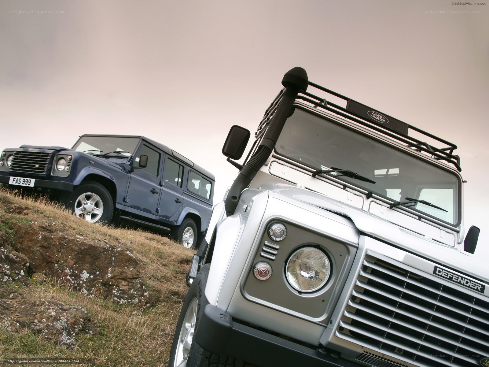 Two Land Rover Defenders on a hill