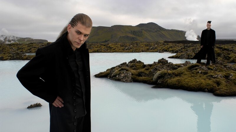 Two men in black coats at a geothermal pool