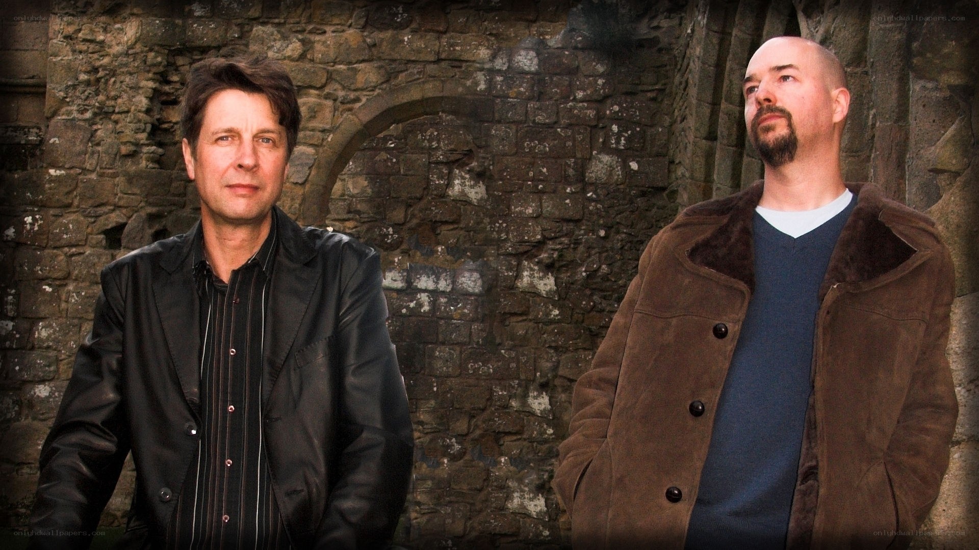 two men in front of stone wall