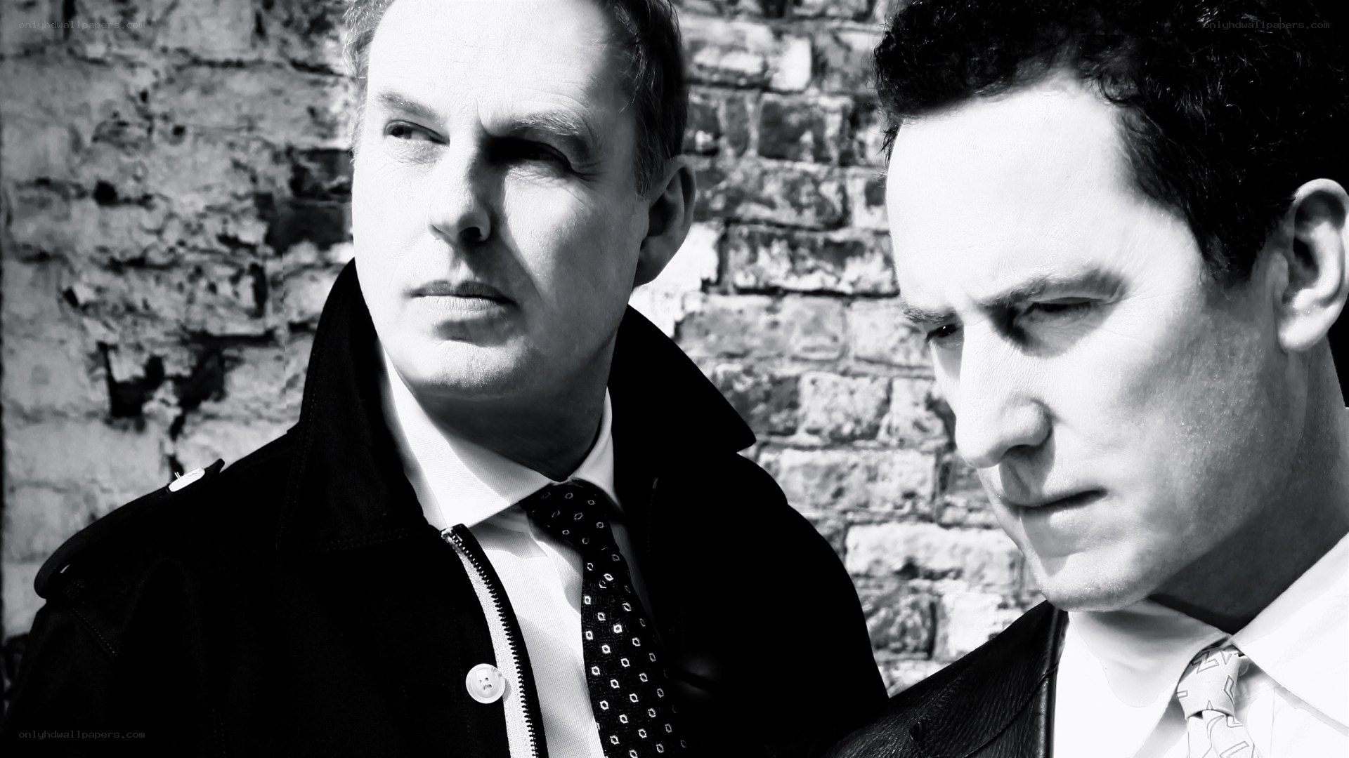 two men in suits against brick wall