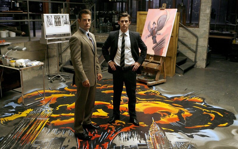 Two men in suits stand on a cityscape painting