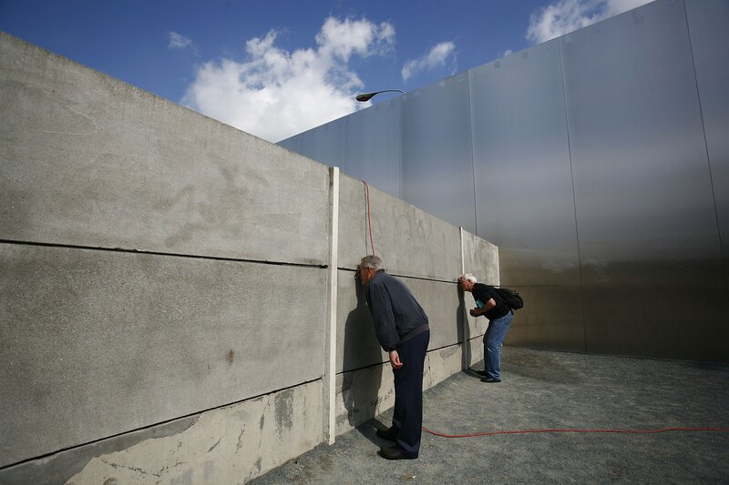 Two men inspecting a wall