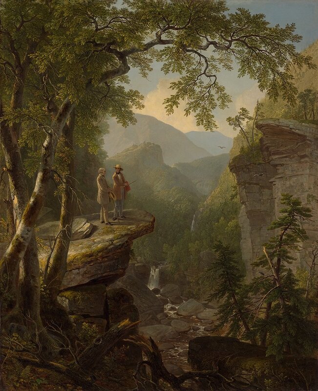 Two men on a cliff overlooking a valley