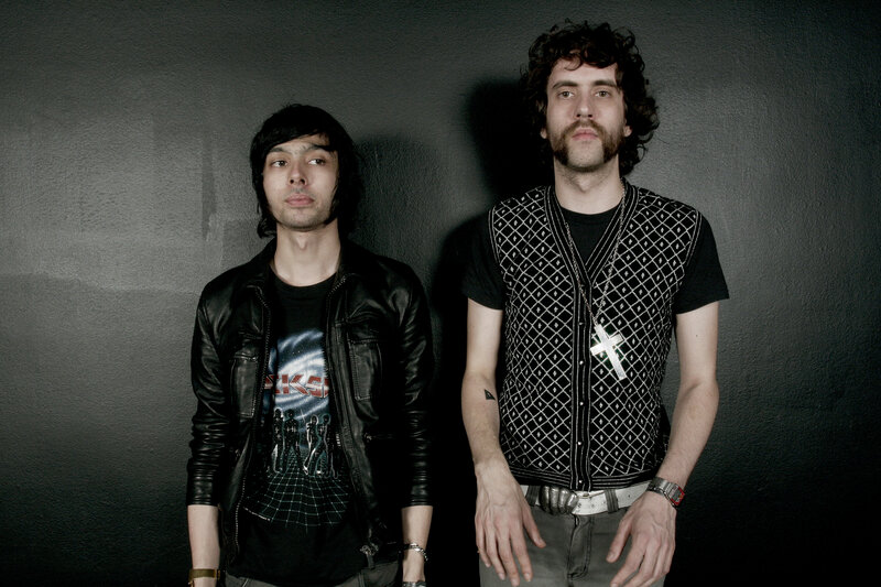 two men posing against a wall