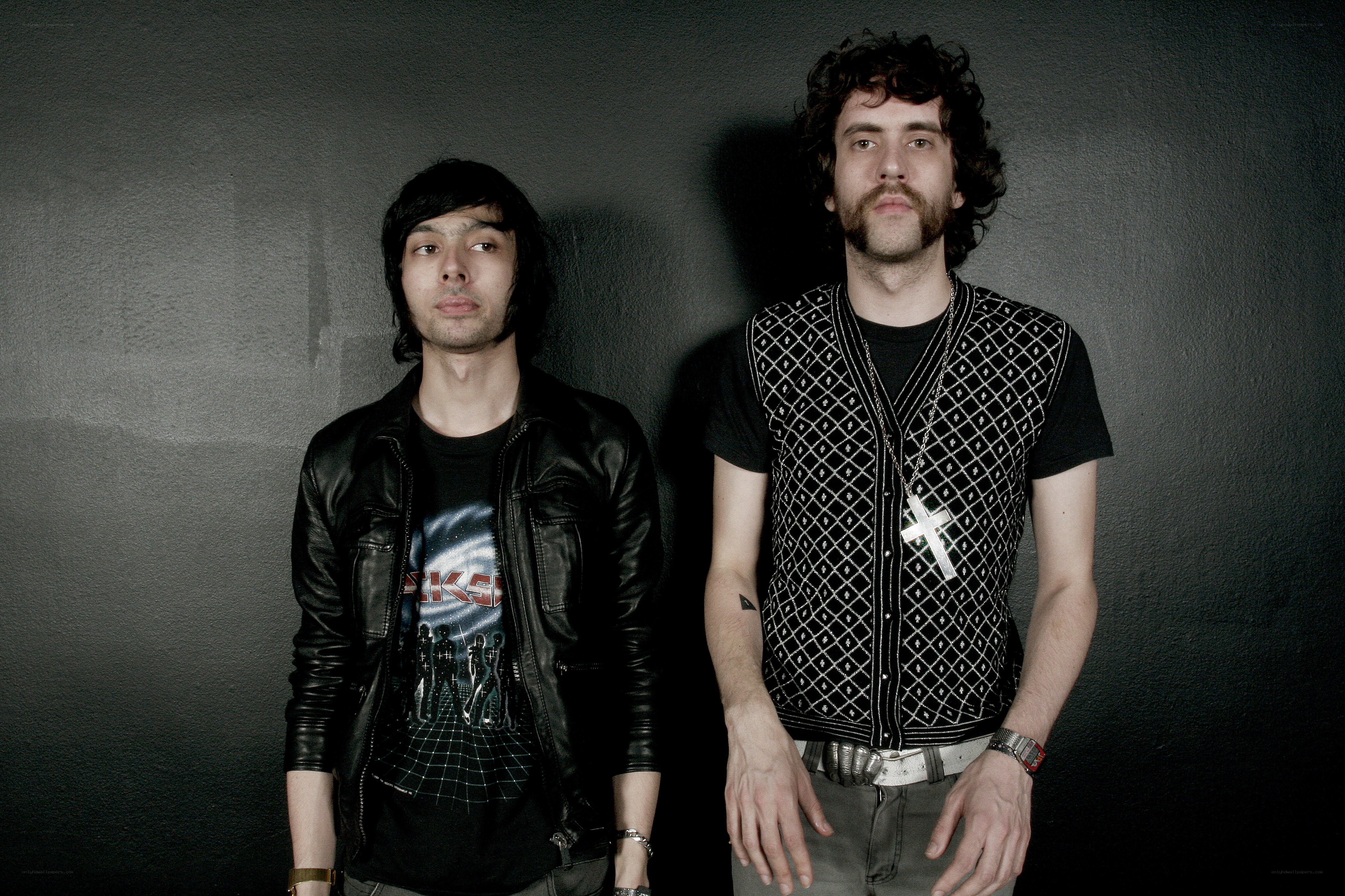 two men posing against a wall