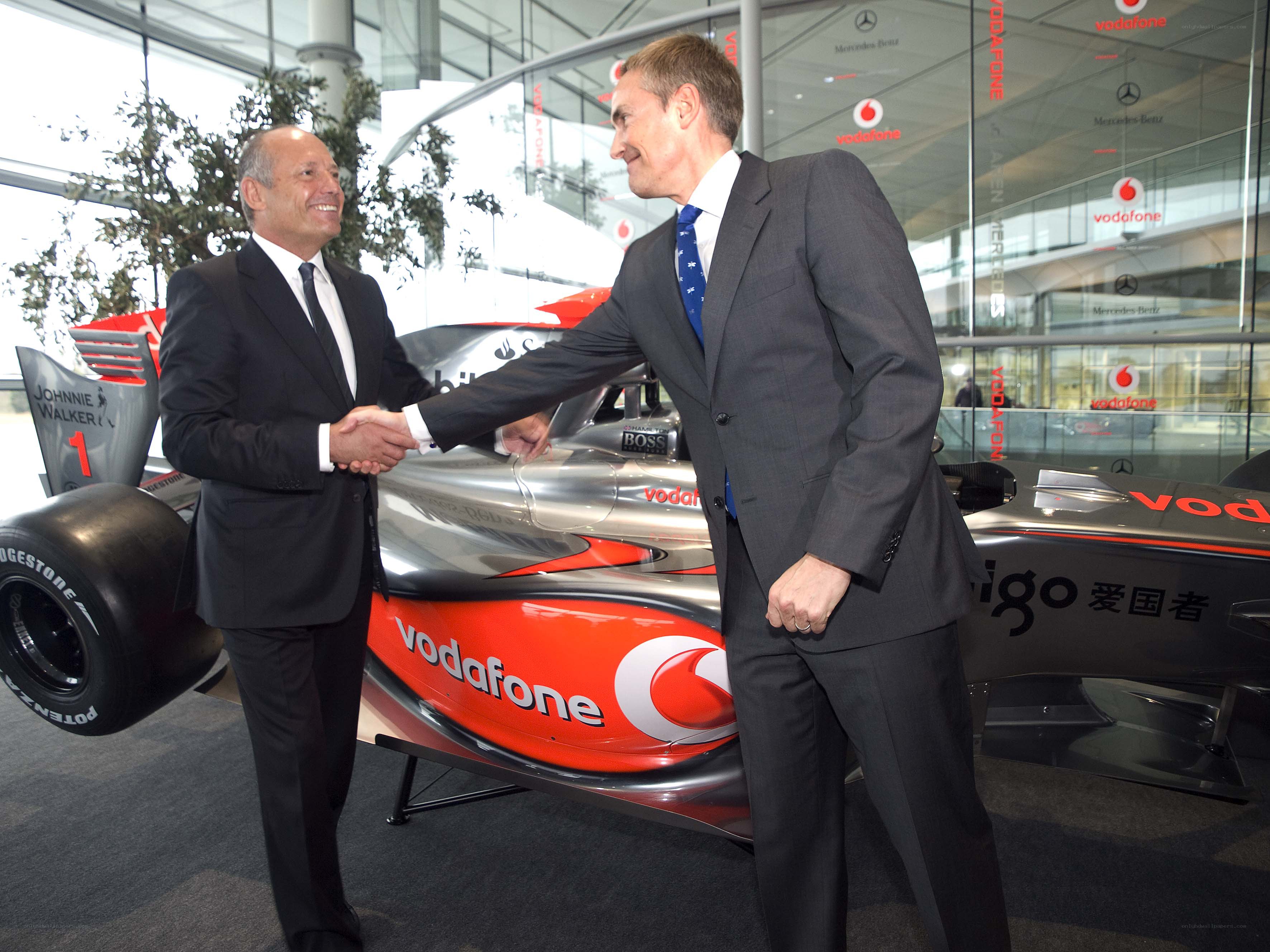Two men shaking hands by a race car