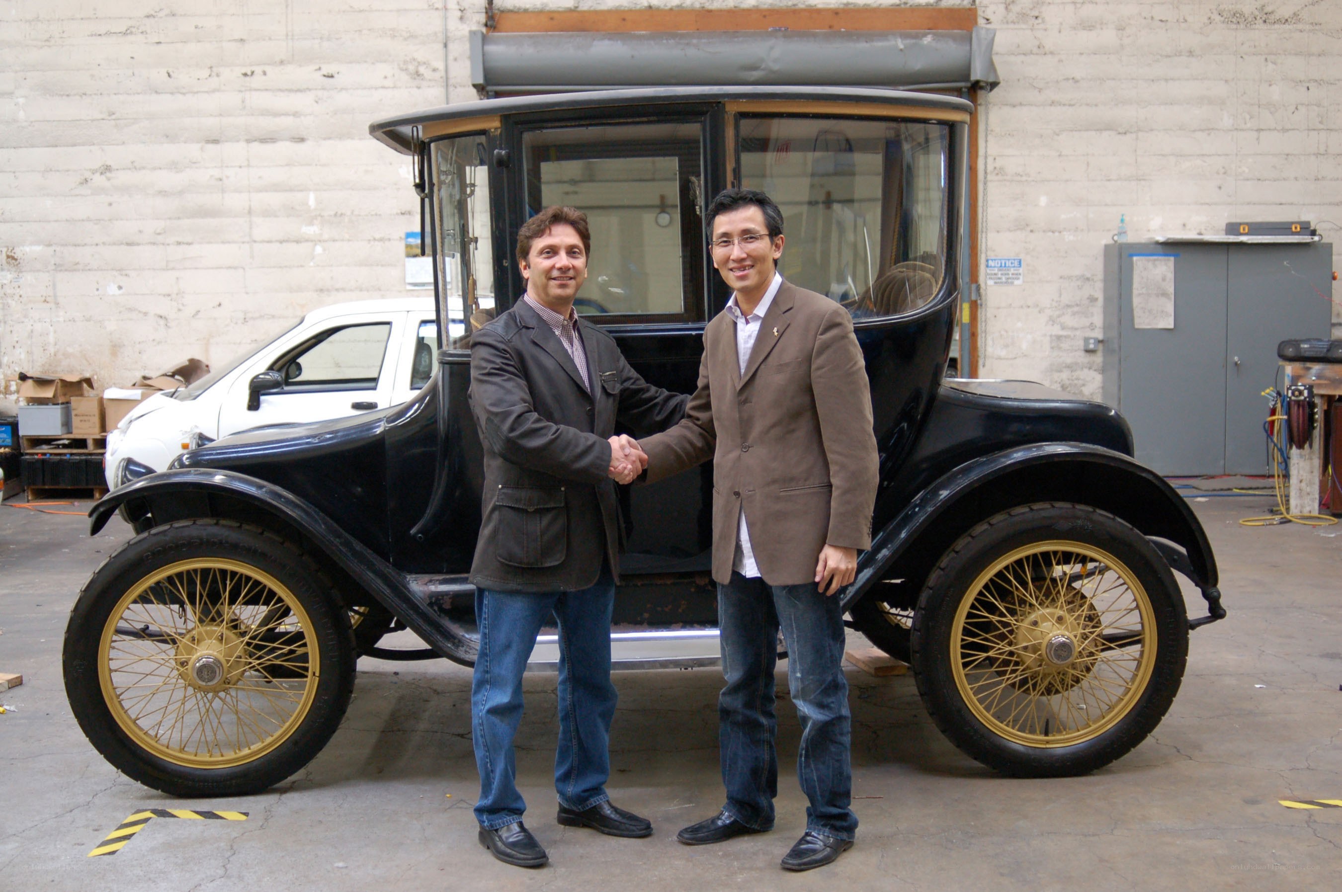 Two men shaking hands by vintage car