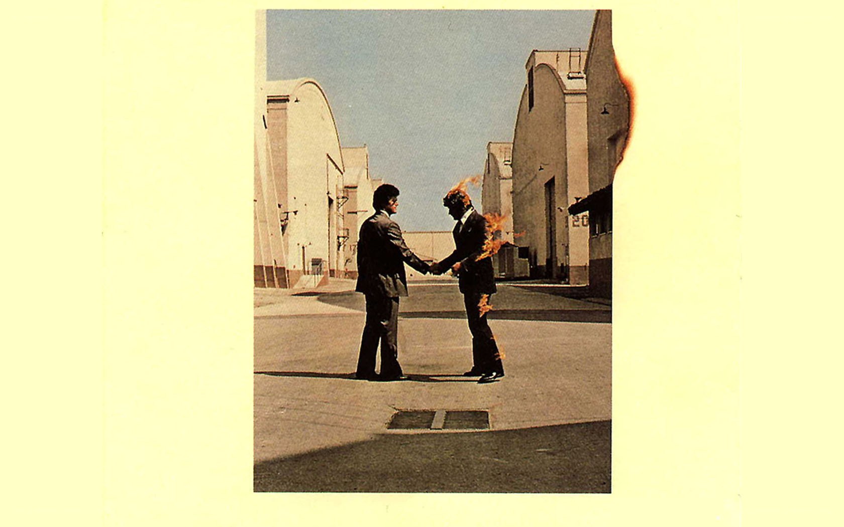 Two men shaking hands with one on fire