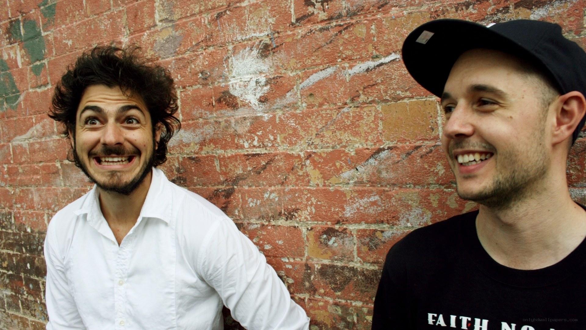 two men smiling by brick wall