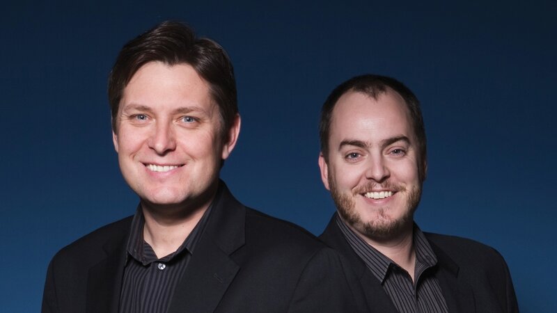two men smiling in suits