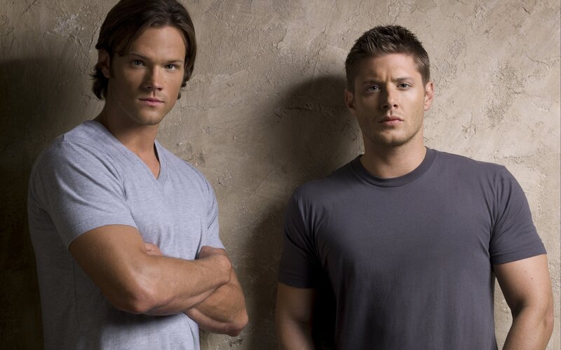 two men standing against wall