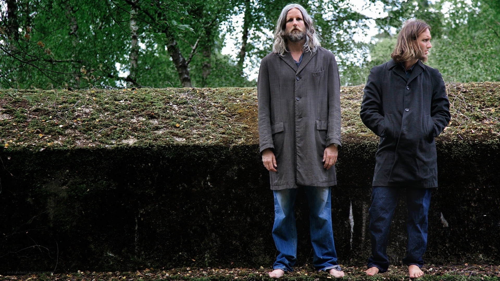 Two men standing barefoot in forest