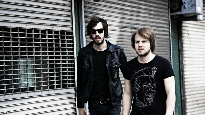 two men standing in front of shuttered building