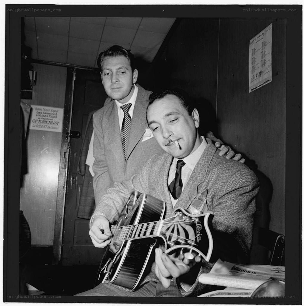 Two men with a guitar in a room
