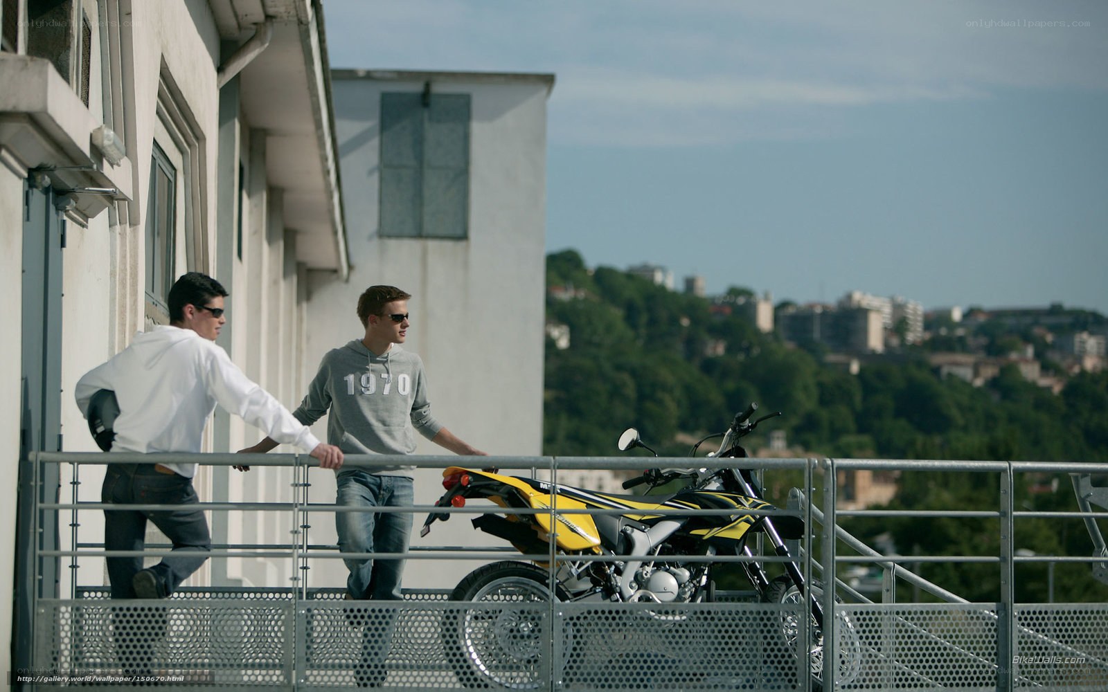 Two men with a motorcycle on a balcony