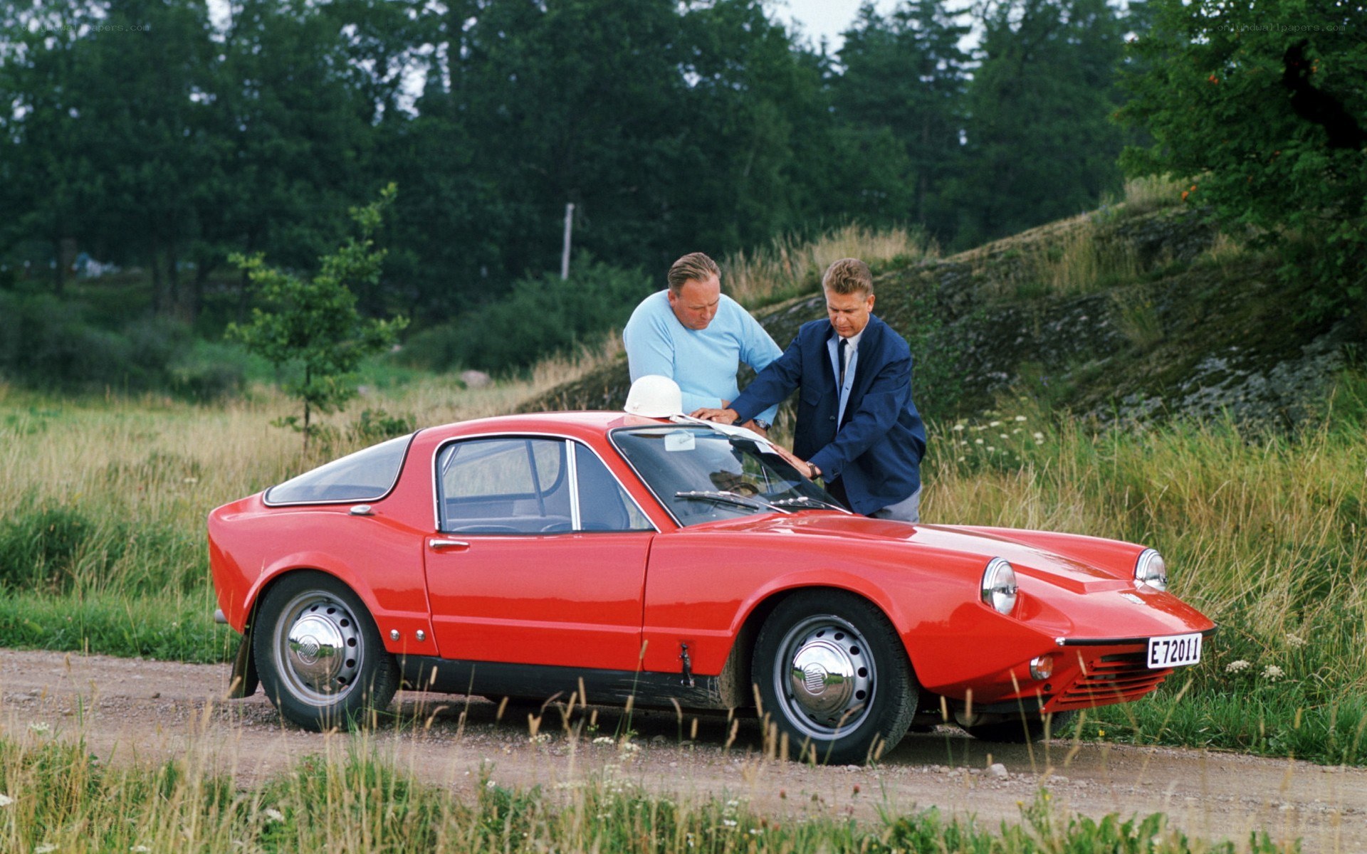 Two men with a red sports car