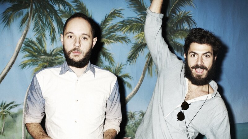 Two men with beards in front of palm trees