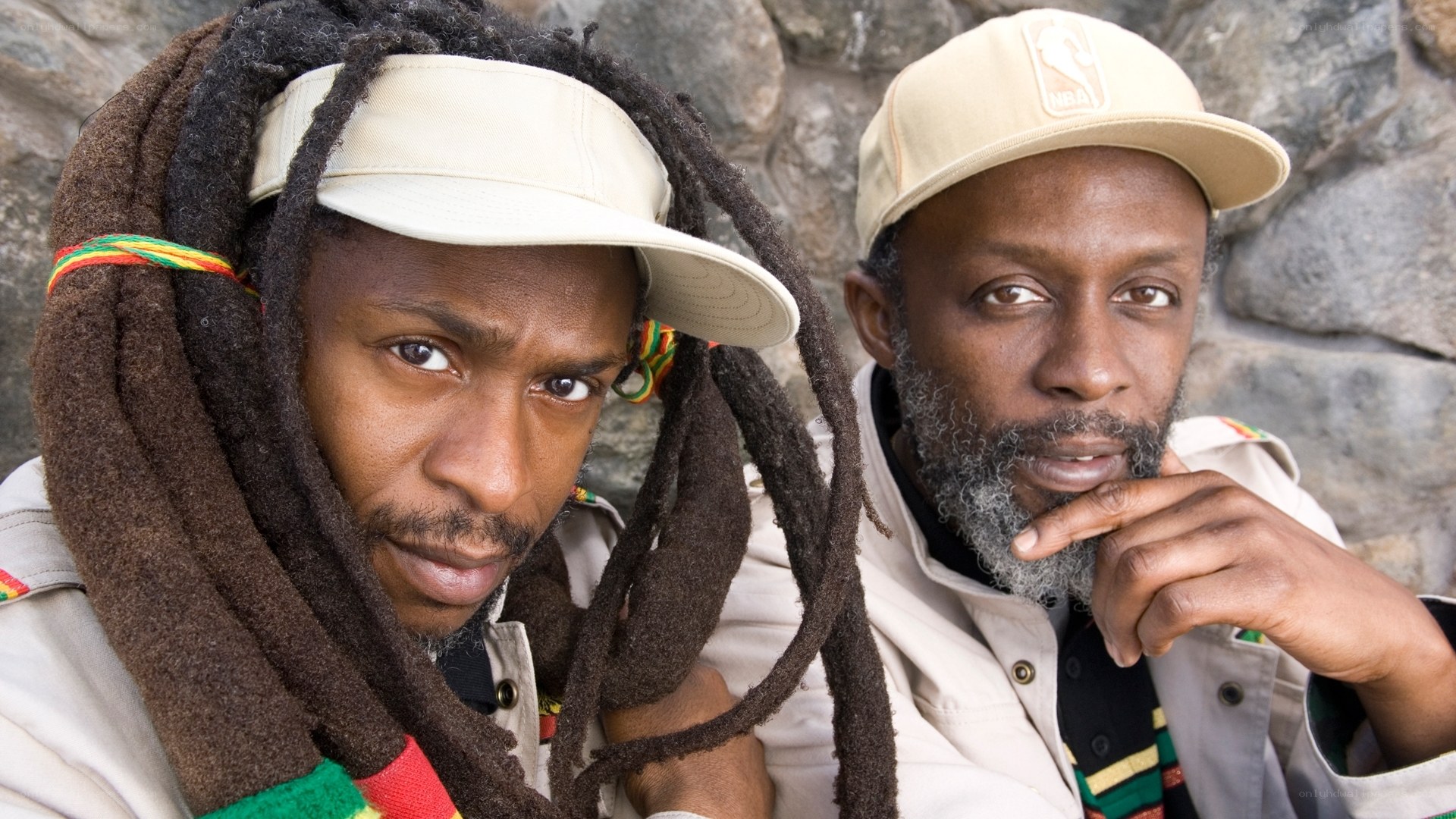 Two men with dreadlocks and caps