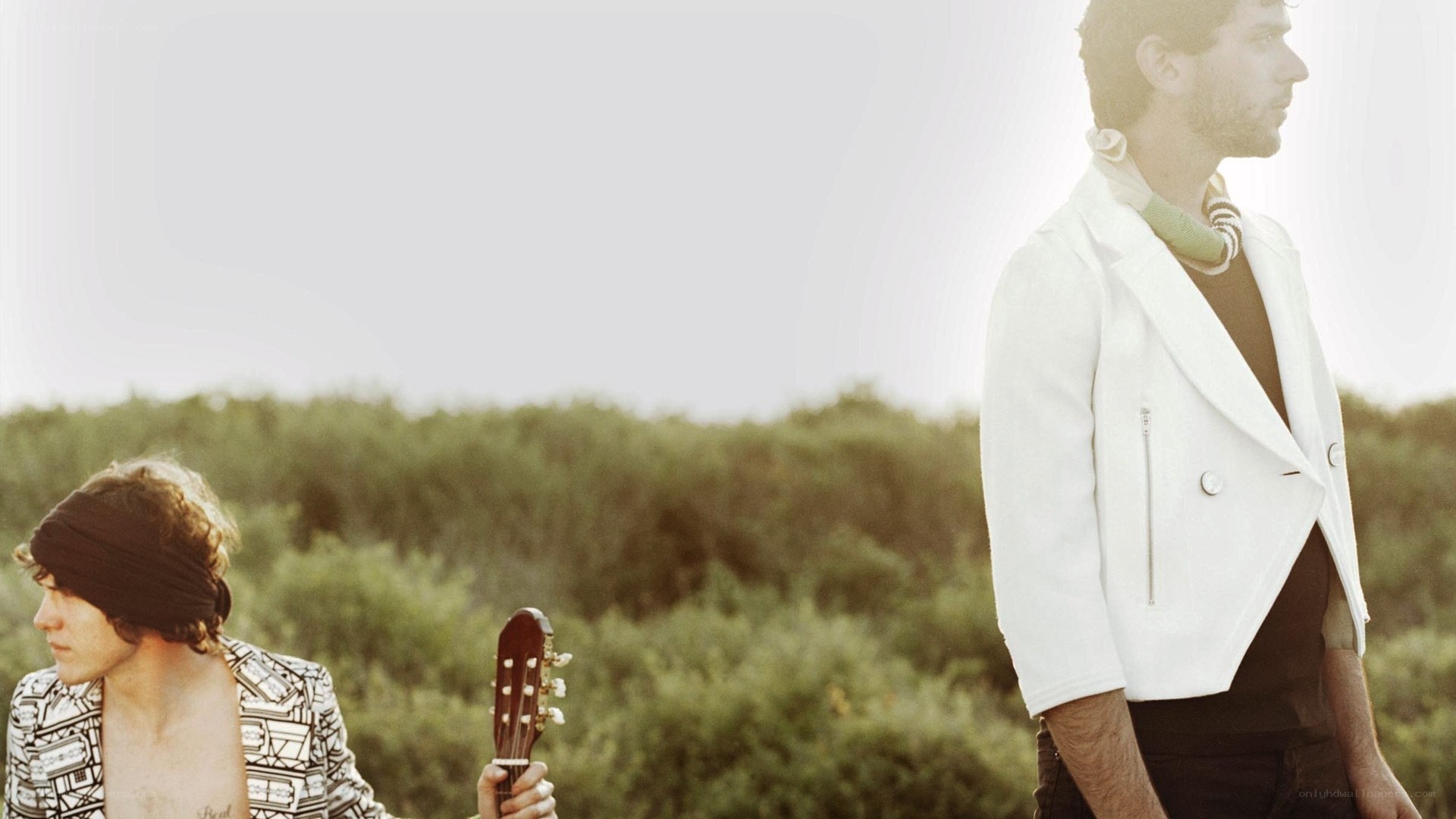 Two men with guitar in field