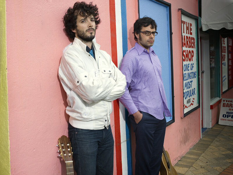 Two men with guitars outside a barber shop