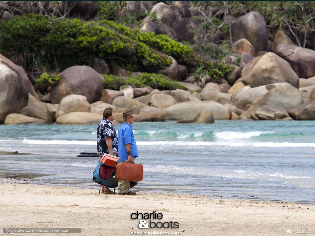 Two men with luggage on beach