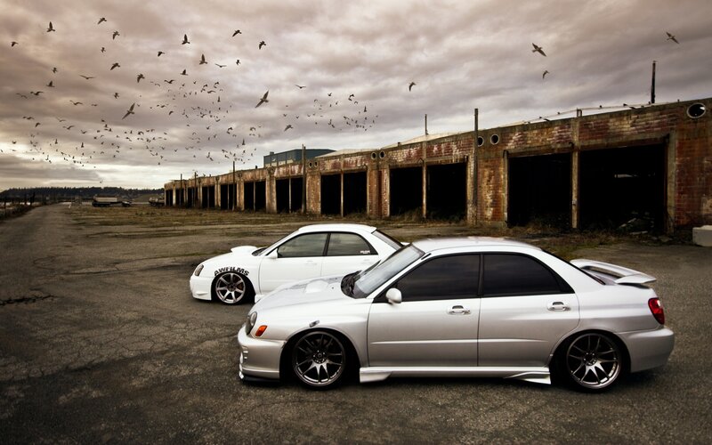 Two modified cars in an abandoned lot