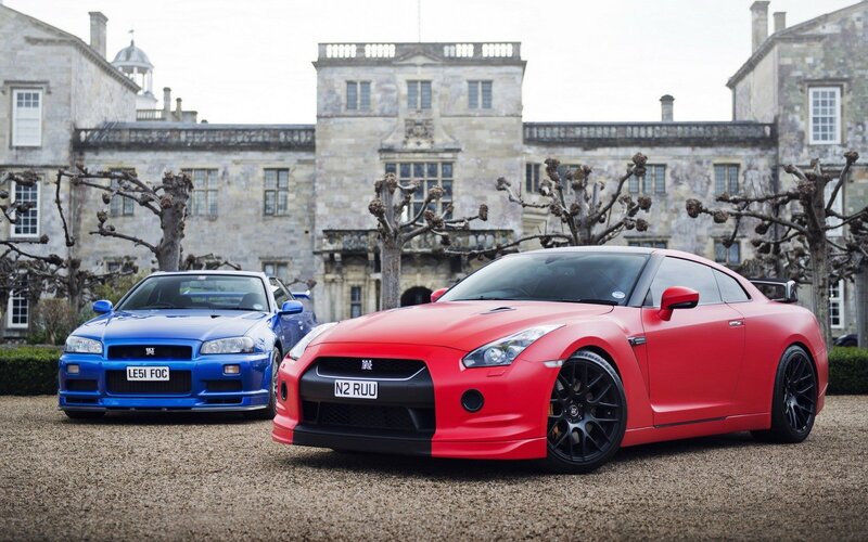 Two Nissan GT-Rs in front of a mansion