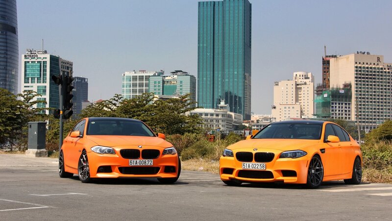 Two orange BMW cars in city