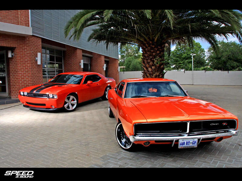 Two orange muscle cars parked