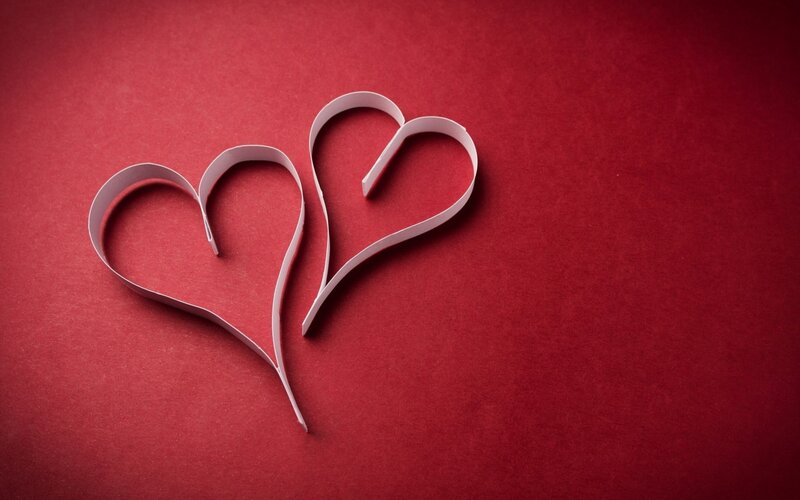 Two paper hearts on red