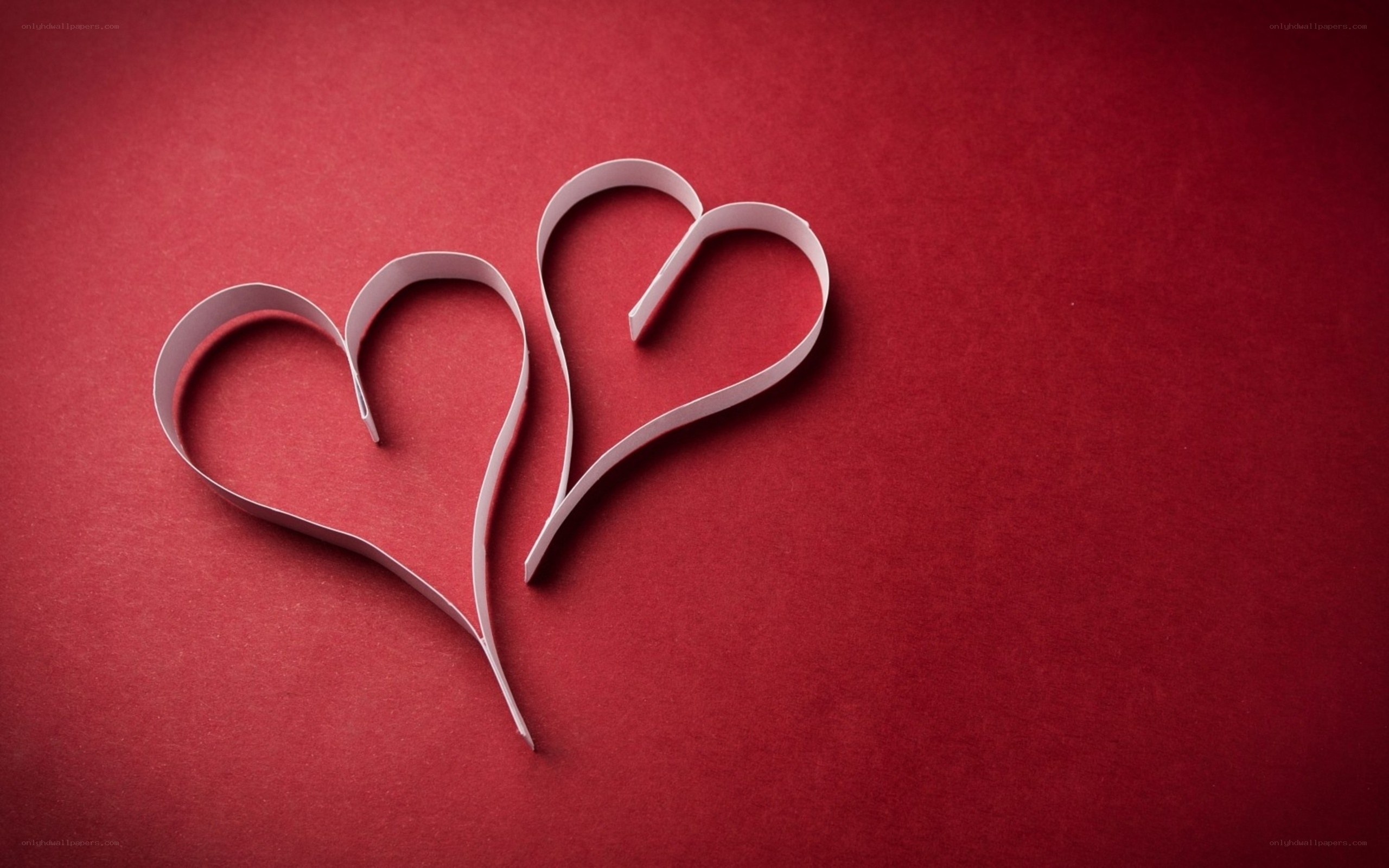 Two paper hearts on red