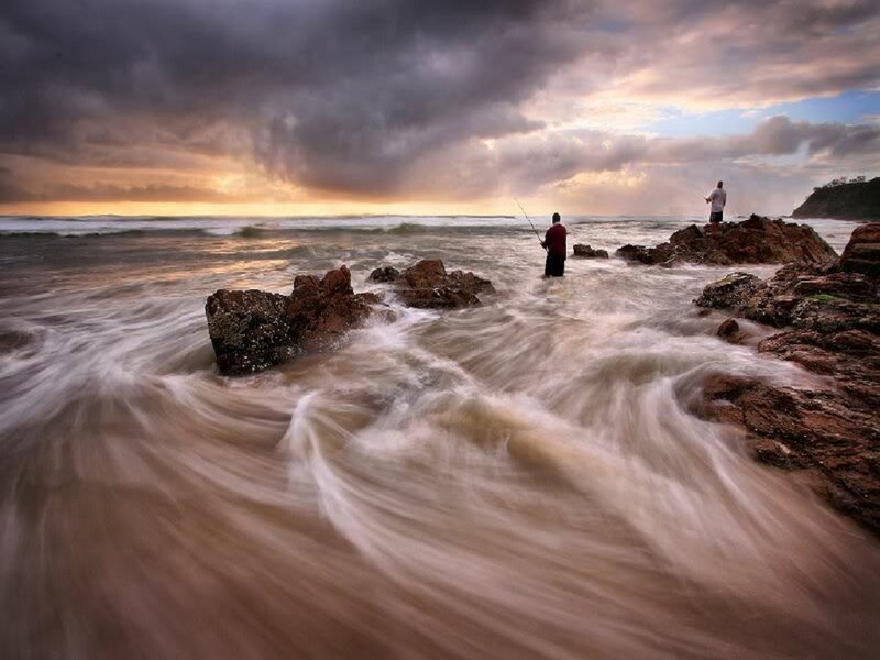 Two People Fishing on Rocks