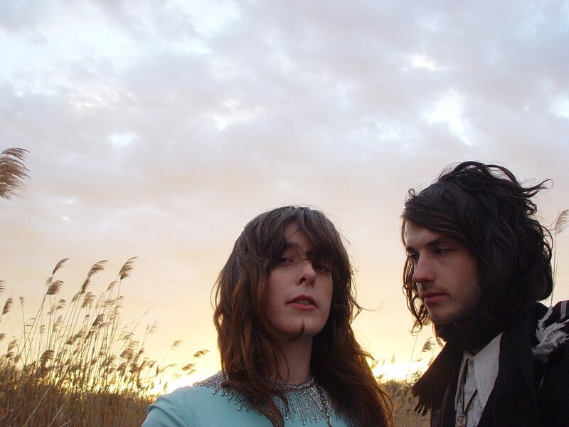 two people in a field at sunset