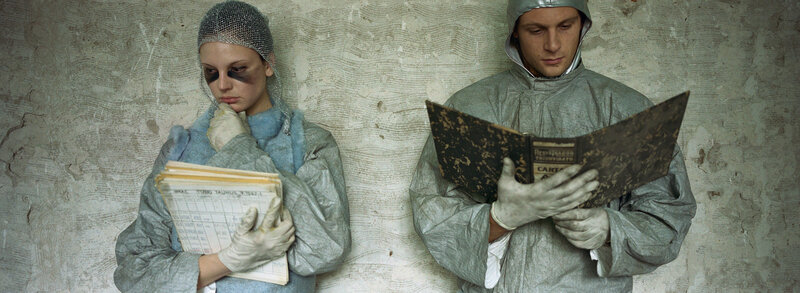 Two people in protective suits reading