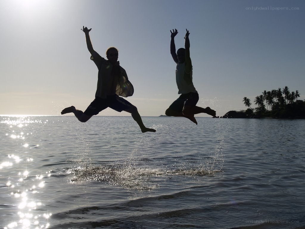 Two people jumping on a beach