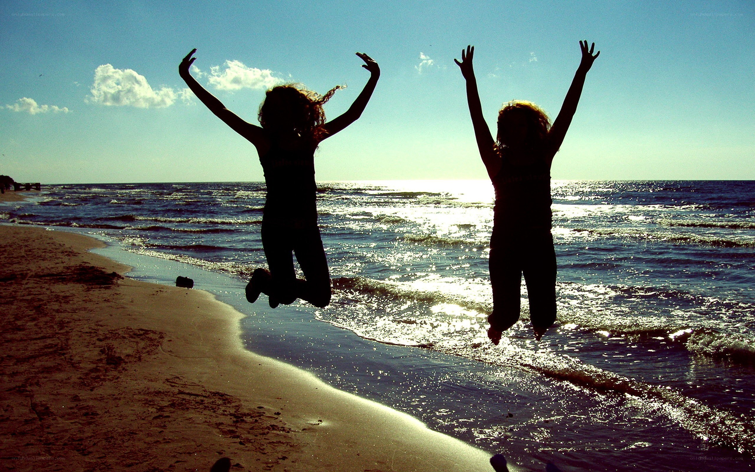 Two people jumping on the beach
