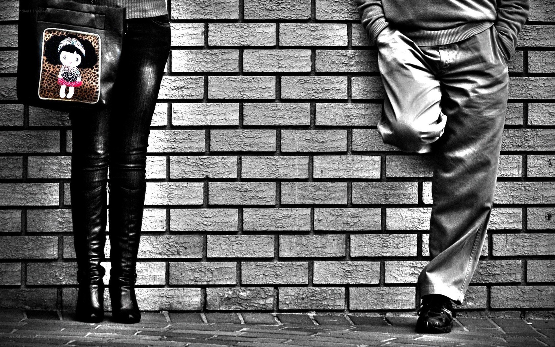 Two people leaning against a brick wall