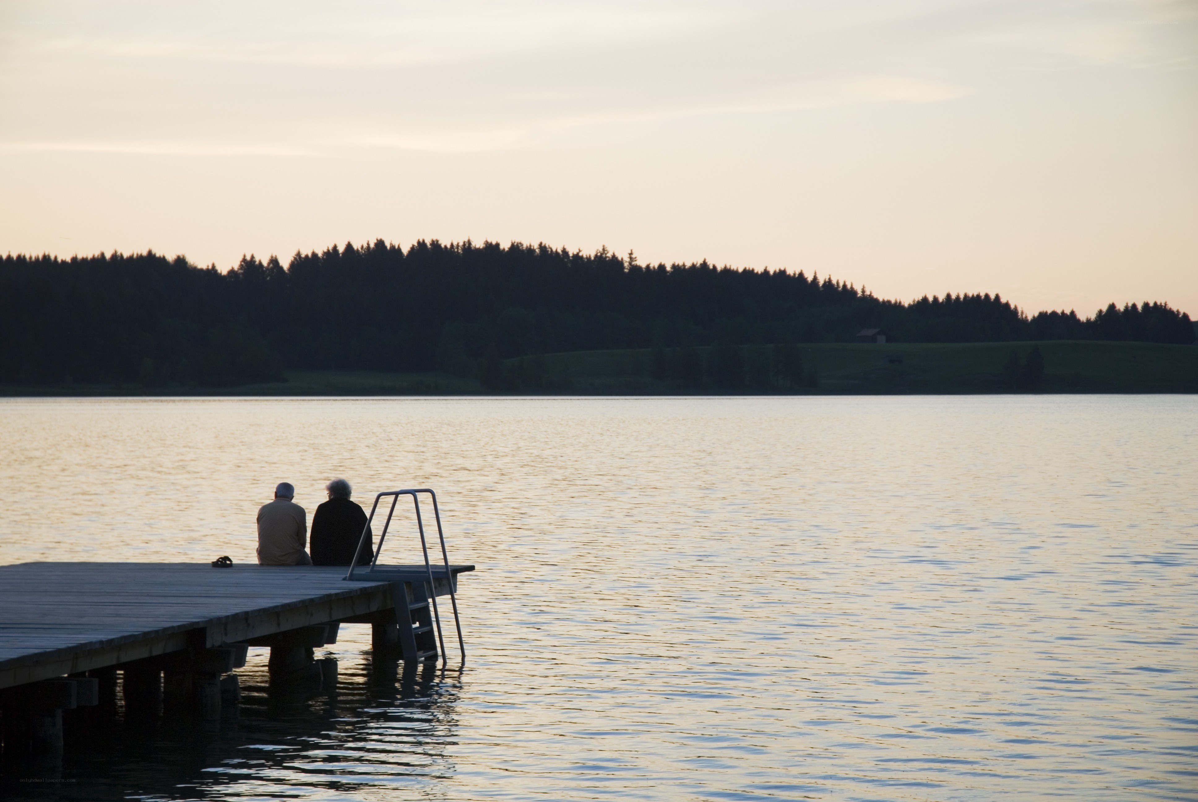 Two people on a dock at sunset