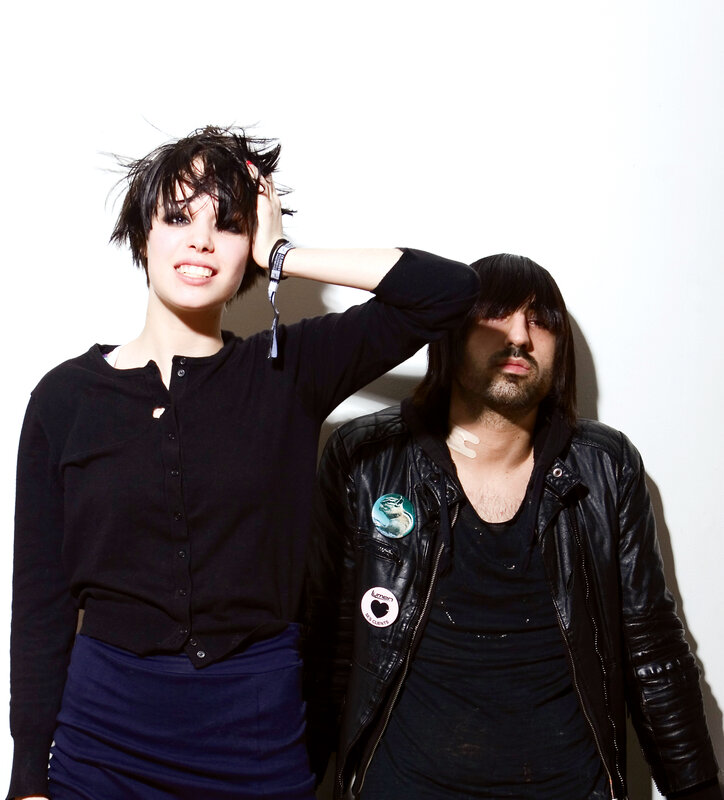 two people posing against a white wall