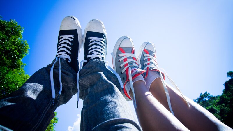 two people's feet in sneakers