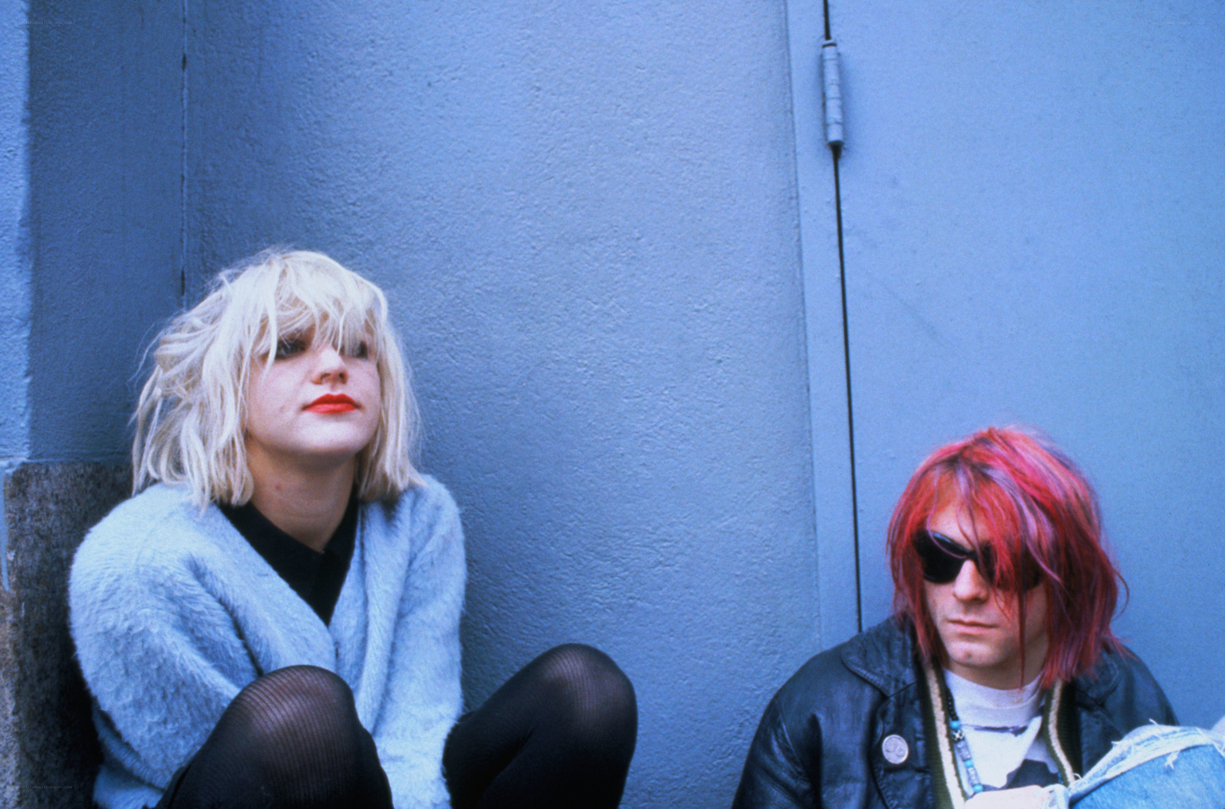 Two people sitting against a wall
