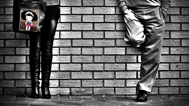 two people standing by a brick wall